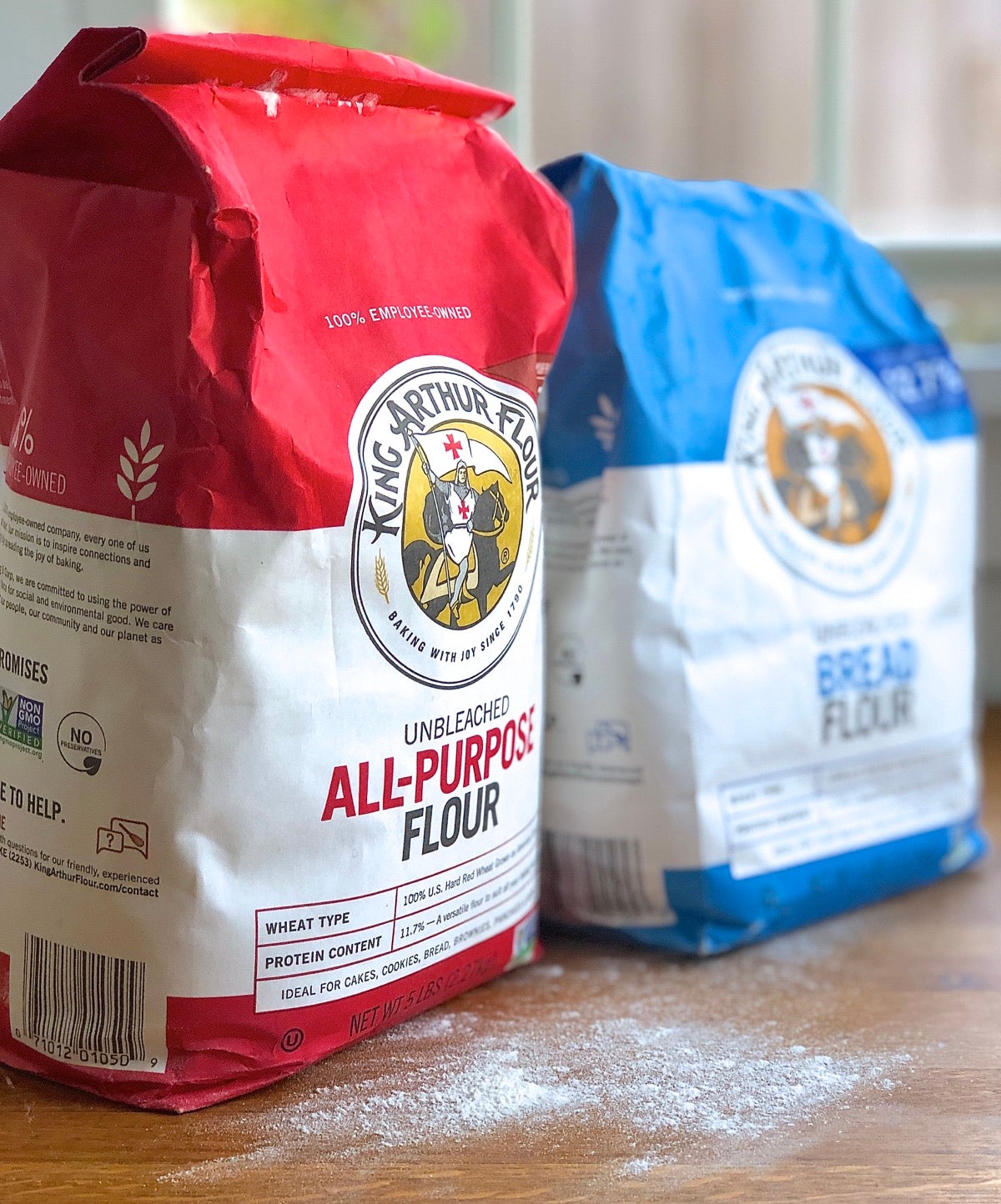 Bags of King Arthur all-purpose flour and bread flour on a table.