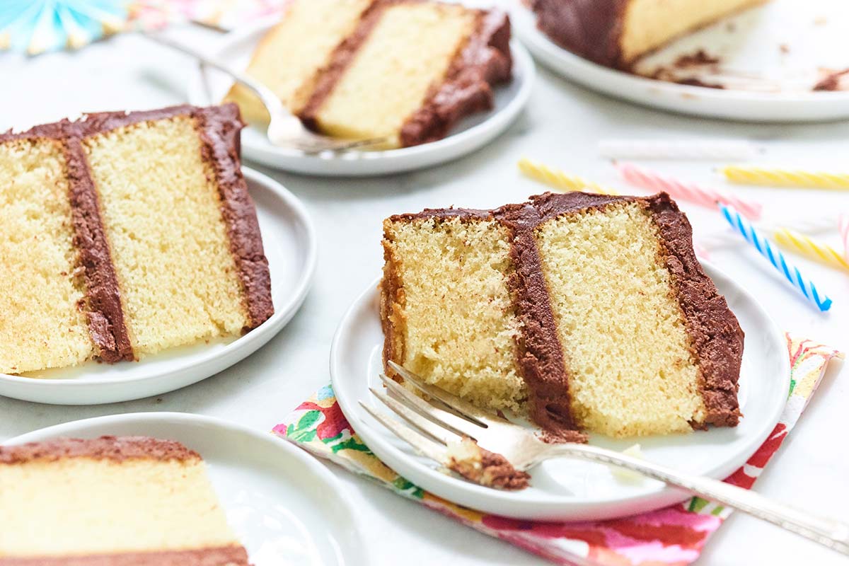 Slices of yellow cake with chocolate frosting on small plates