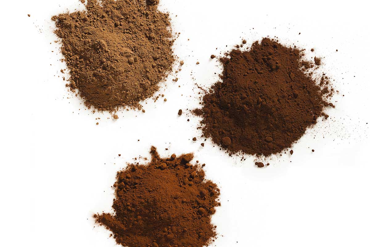 Three piles of different cocoa powders, one dark in color, one medium, and one light