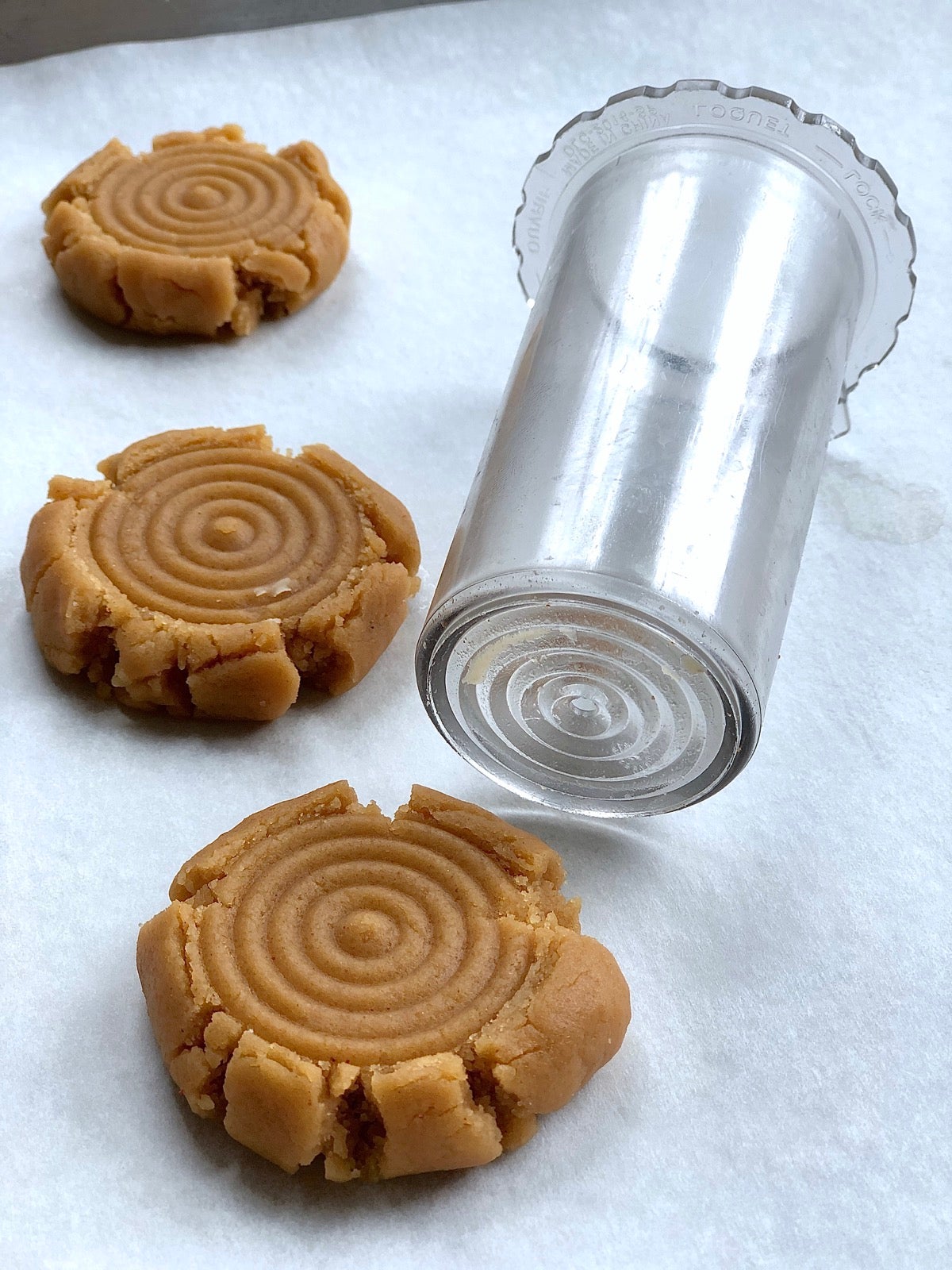 Puher from a food processor being used to imprint a design on the top of balls of shortbread dough.