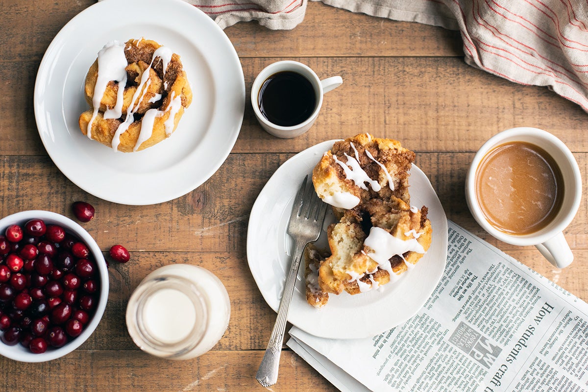 A breakfast scene complete with two plates of gluten-free cinnamon rolls and coffee