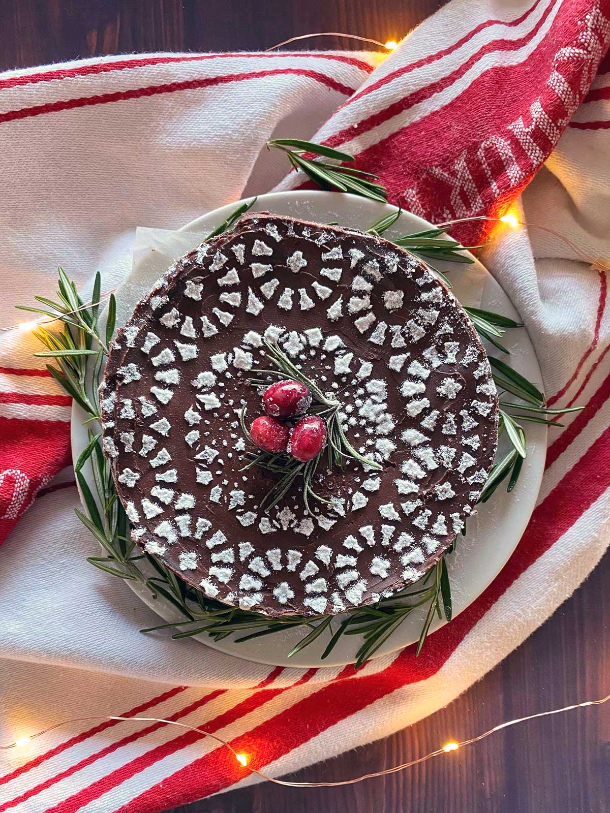A flourless chocolate cake dressed up with a stenciled design on top and sugared cranberries for garnish