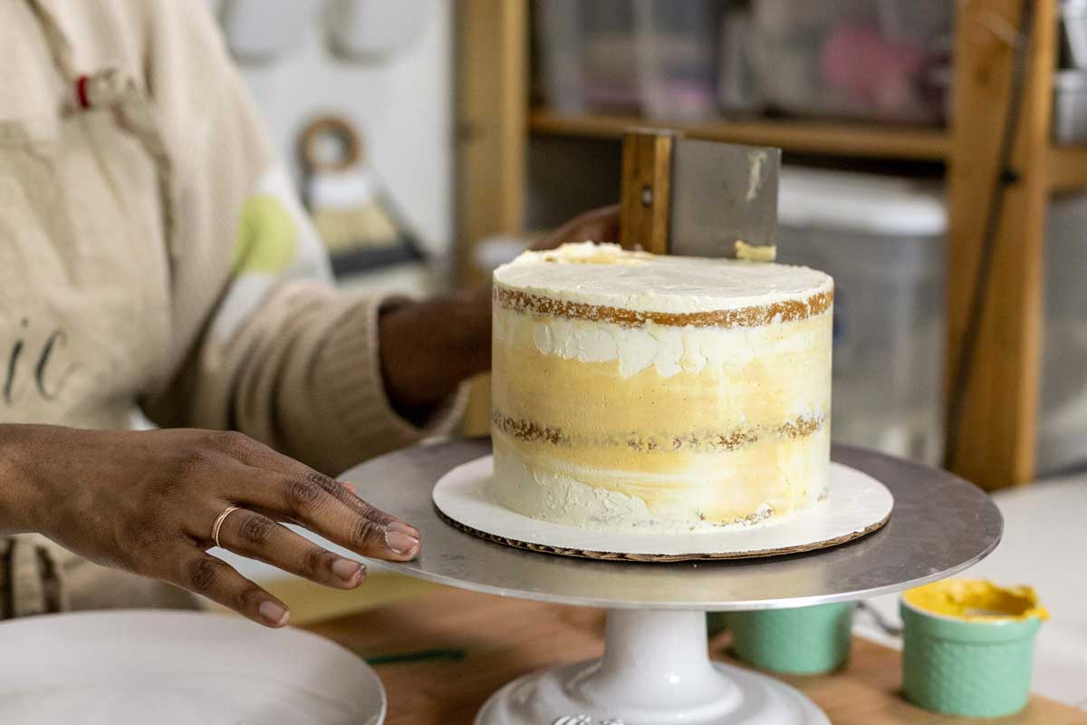 Smoothing colored frosting layer onto cake