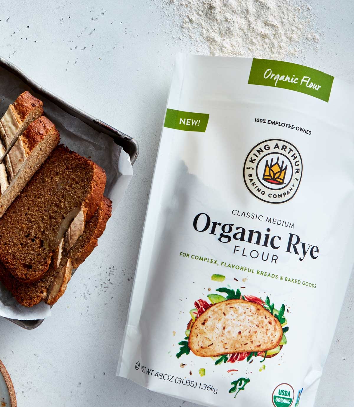 Bag of Organic Medium Rye Flour, next to a loaf of banana bread