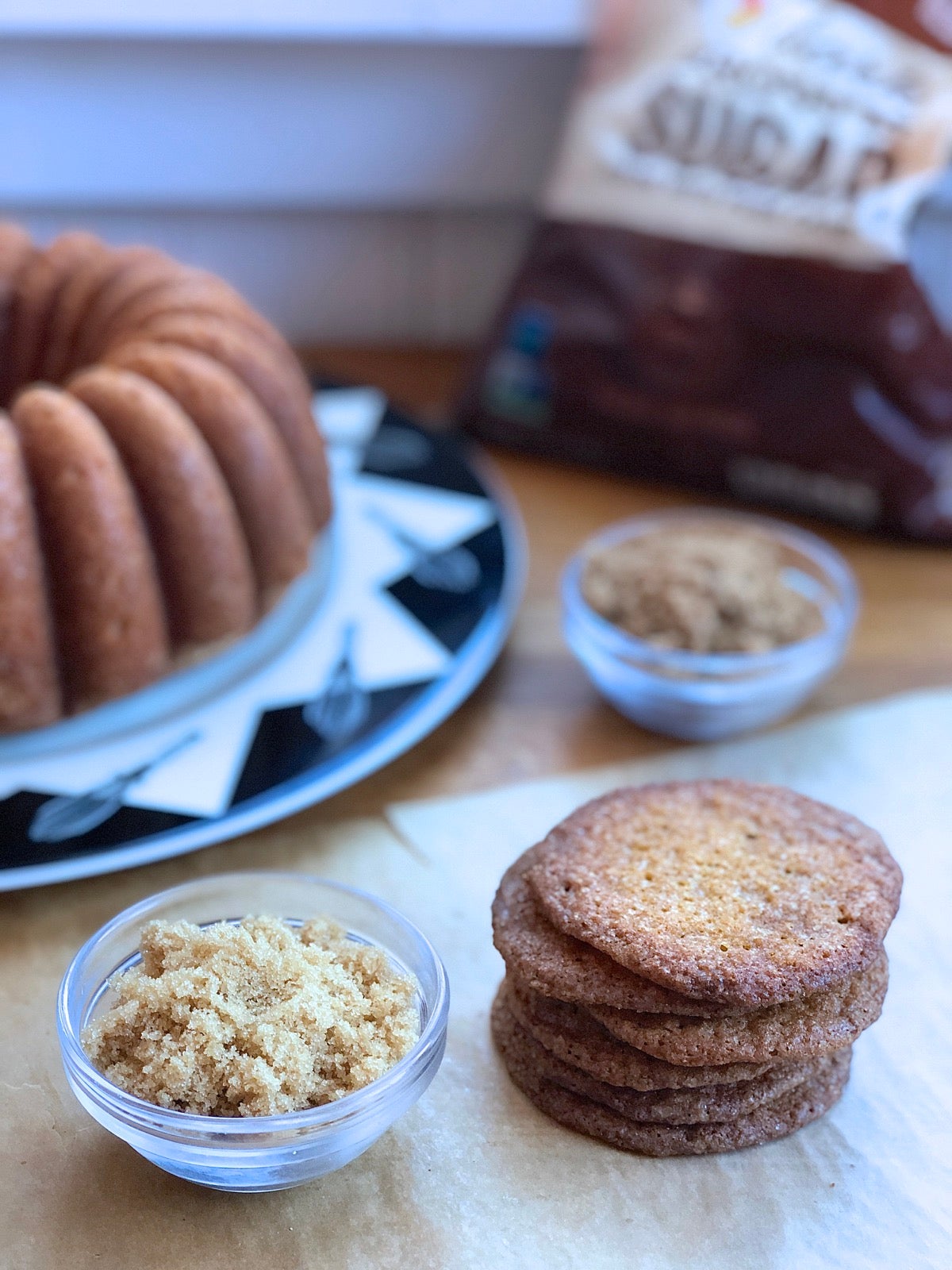 Brown sugar pound cake and buttersnap cookies on a table, bag of brown sugar in the background.