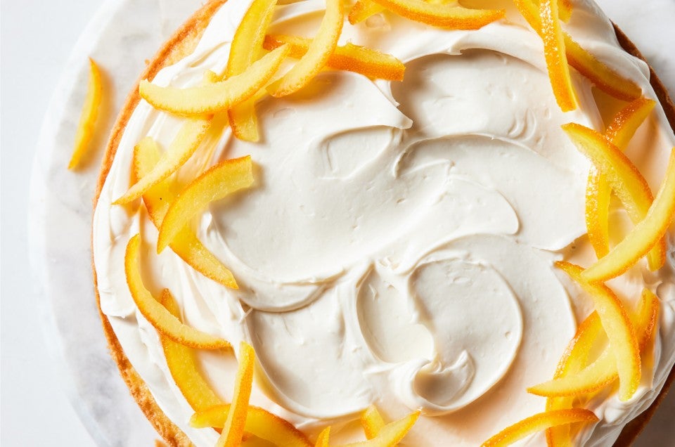 Close up of a layer cake garnished with candied oranges and a cream filling - select to zoom