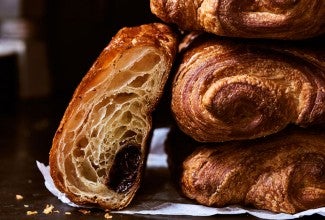 A stack of pain au chocolat with one cut into showing the structure