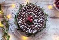 A flourless chocolate cake stenciled with confectioners' sugar, cranberries, and twinkling lights