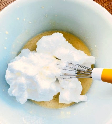 Whipped egg whites added to pancake batter, ready to stir in.