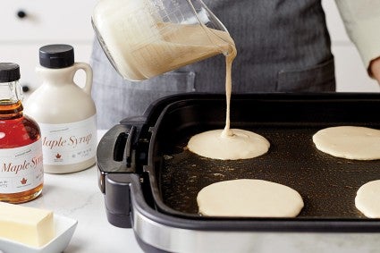 Baker pouring pancake batter onto an electric griddle