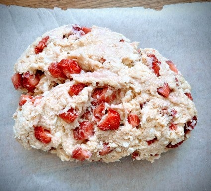 Finished scone dough showing lots of diced fresh strawberries, ready to be shaped.