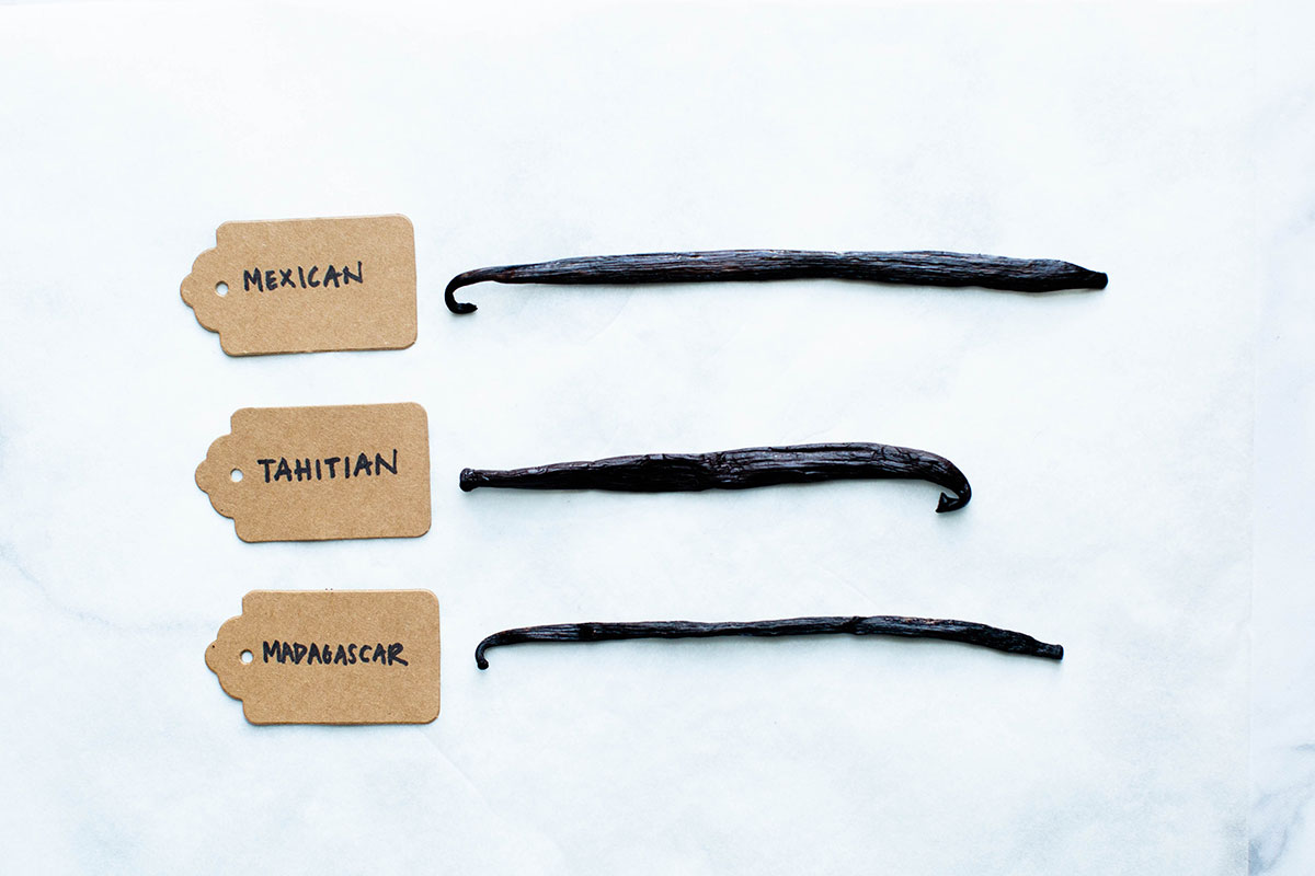 Three varieties of vanilla beans with their labels: Mexican, Tahitian, and Madagascar.
