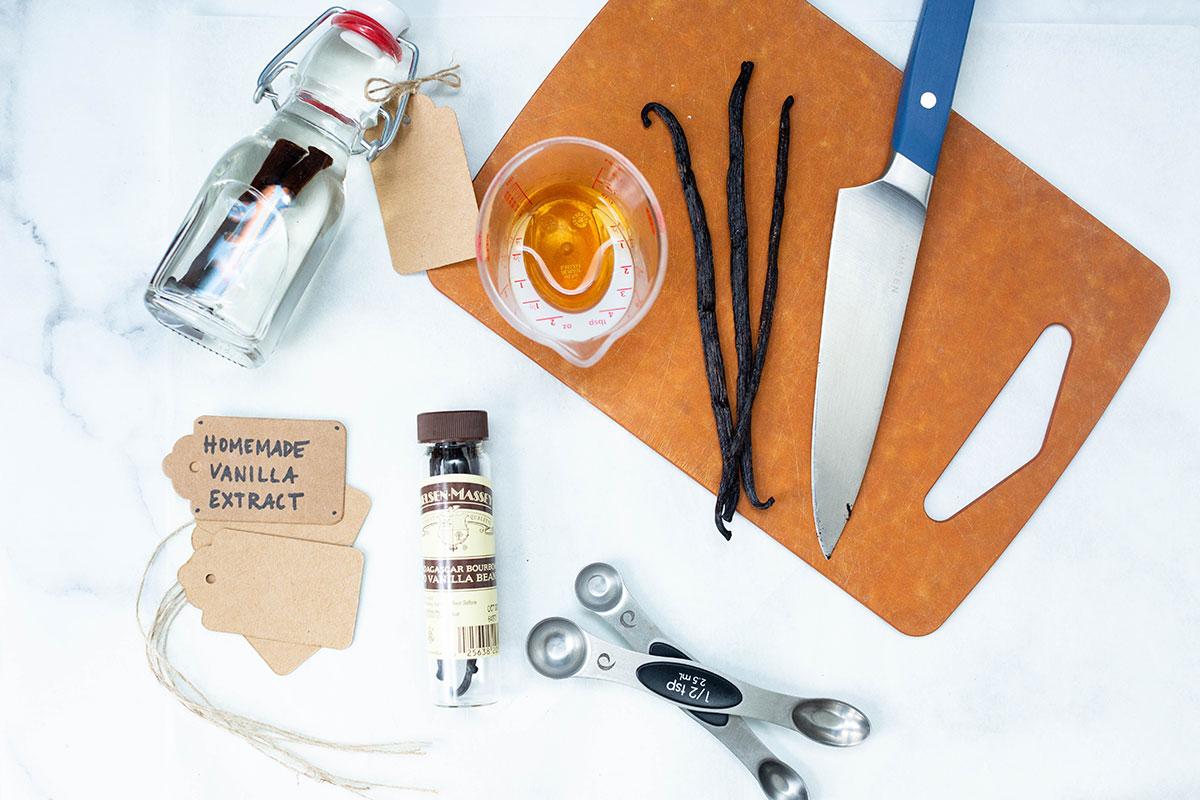 Tools and ingredients needed to make homemade vanilla extract: vanilla beans, a knife, alcohol, and a clean jar.