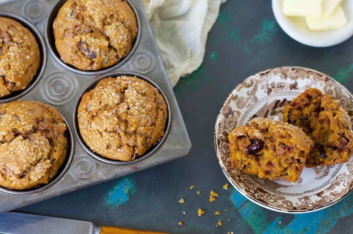 Muffins in a pan and one on a plate, split open.
