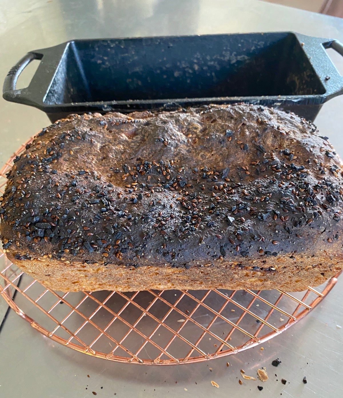 Loaf of bread burned on top in front of black cast iron loaf pan.