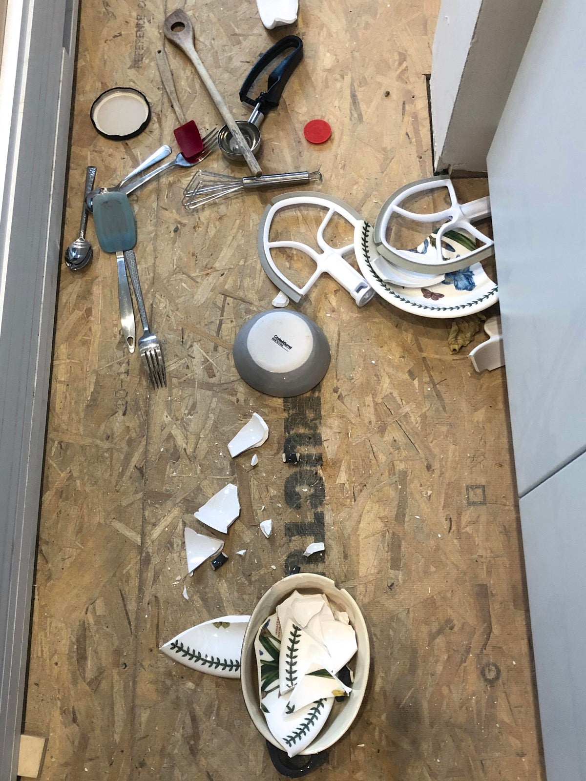 Kitchen floor with broken crockery, spilled silverware, and KitchenAid mixer attachments.