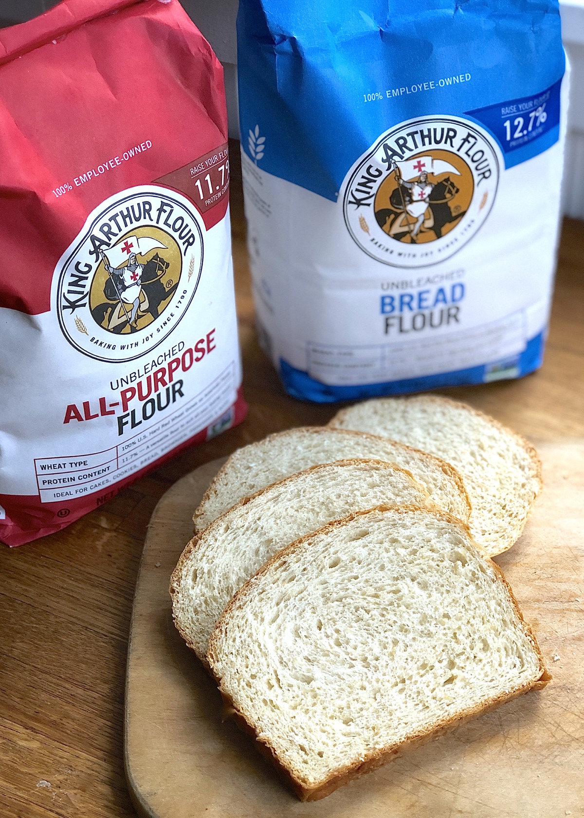 Bags of King Arthur all-purpose flour and bread flour, plus sliced oatmeal bread on a board