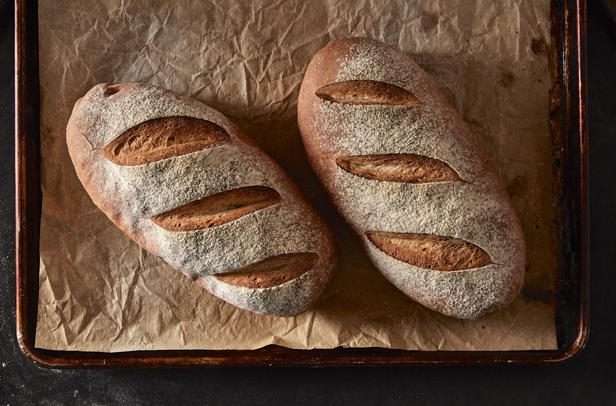 The Easiest Loaf of Bread You'll Ever Bake shaped into two oval loaves, baked on a baking sheet