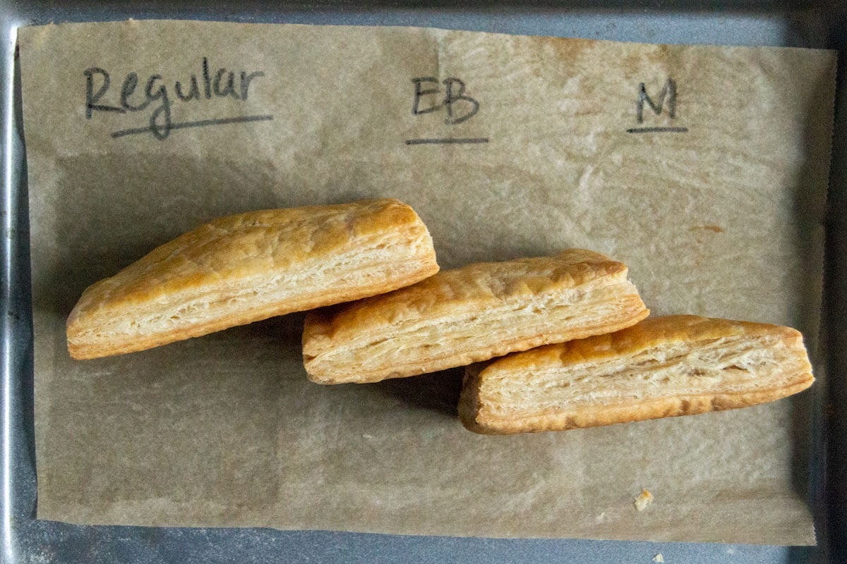 Three small slabs of baked puff pastry made with three different butters, arranged sideways to show their layers.