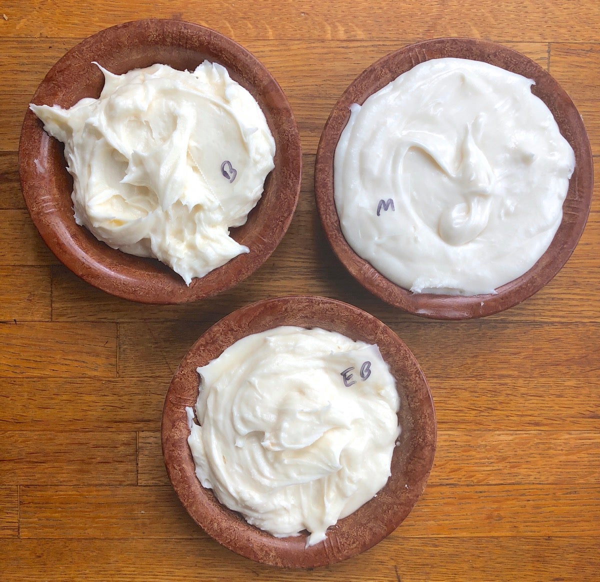 Buttercream frosting in three small bowls, each made with a different type of butter to show differences in color and texture.