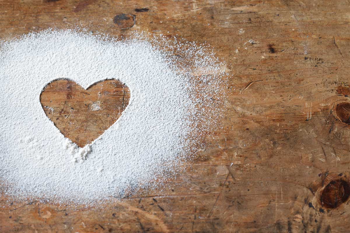 A heart drawn in a dusting of flour on a wooden table