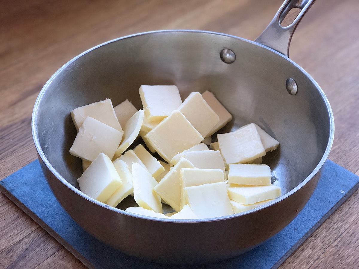 Pats of butter in a light-colored skillet, ready to melt and simmer into brown butter.