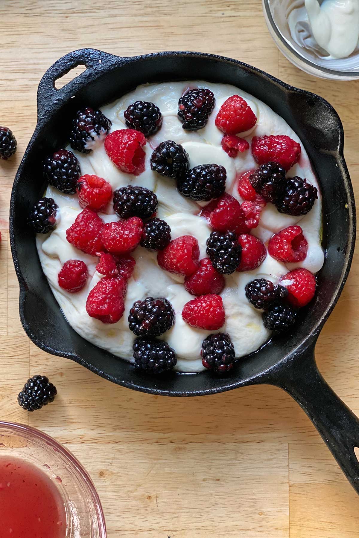 Pizza dough in a cast iron pan topped with sweetened mascarpone and fresh berries