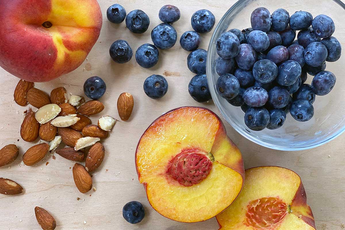 Peaches, blueberries, and almonds on a kitchen table