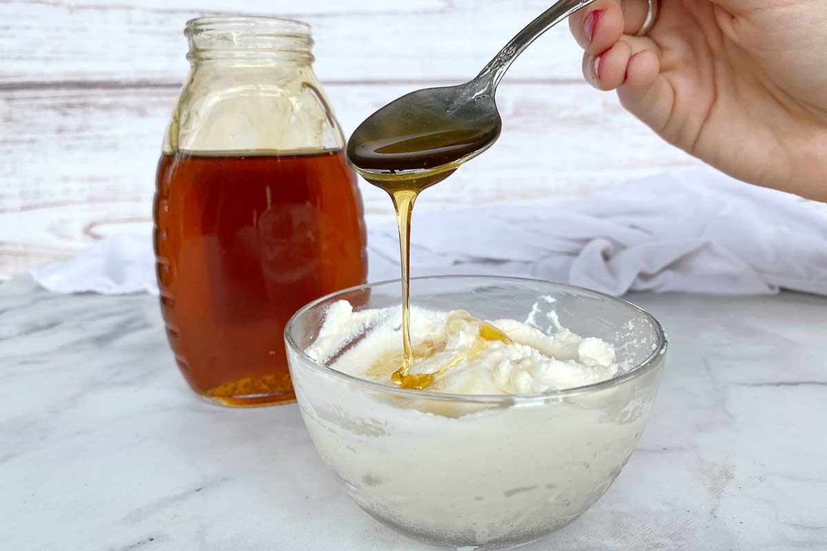 A small bowl of ricotta being drizzled with honey