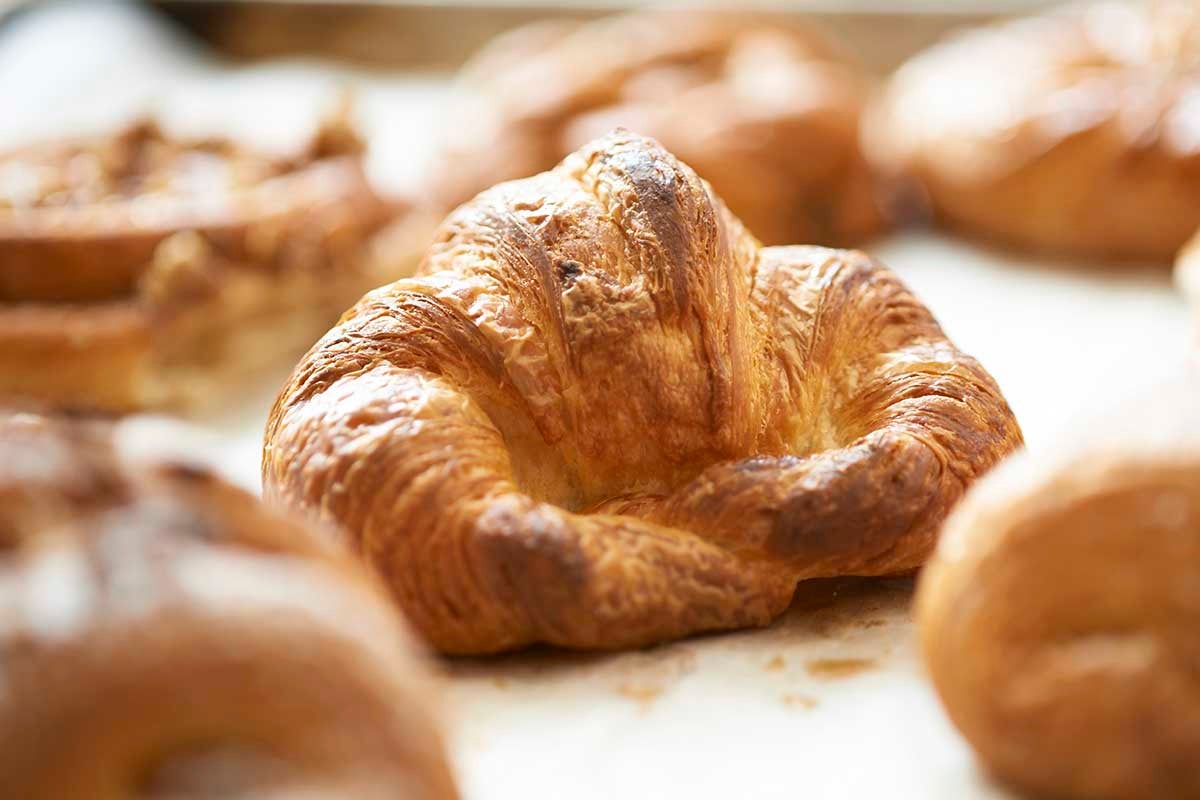 A croissant surrounded by other croissants on a pan