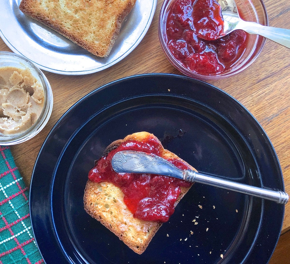 Toast on a plate, spread with butter and strawberry jam.