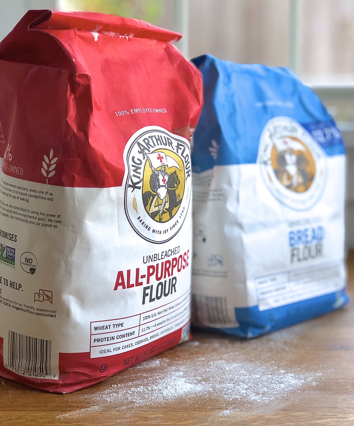 Bags of King Arthur all-purpose flour and bread flour on a table.