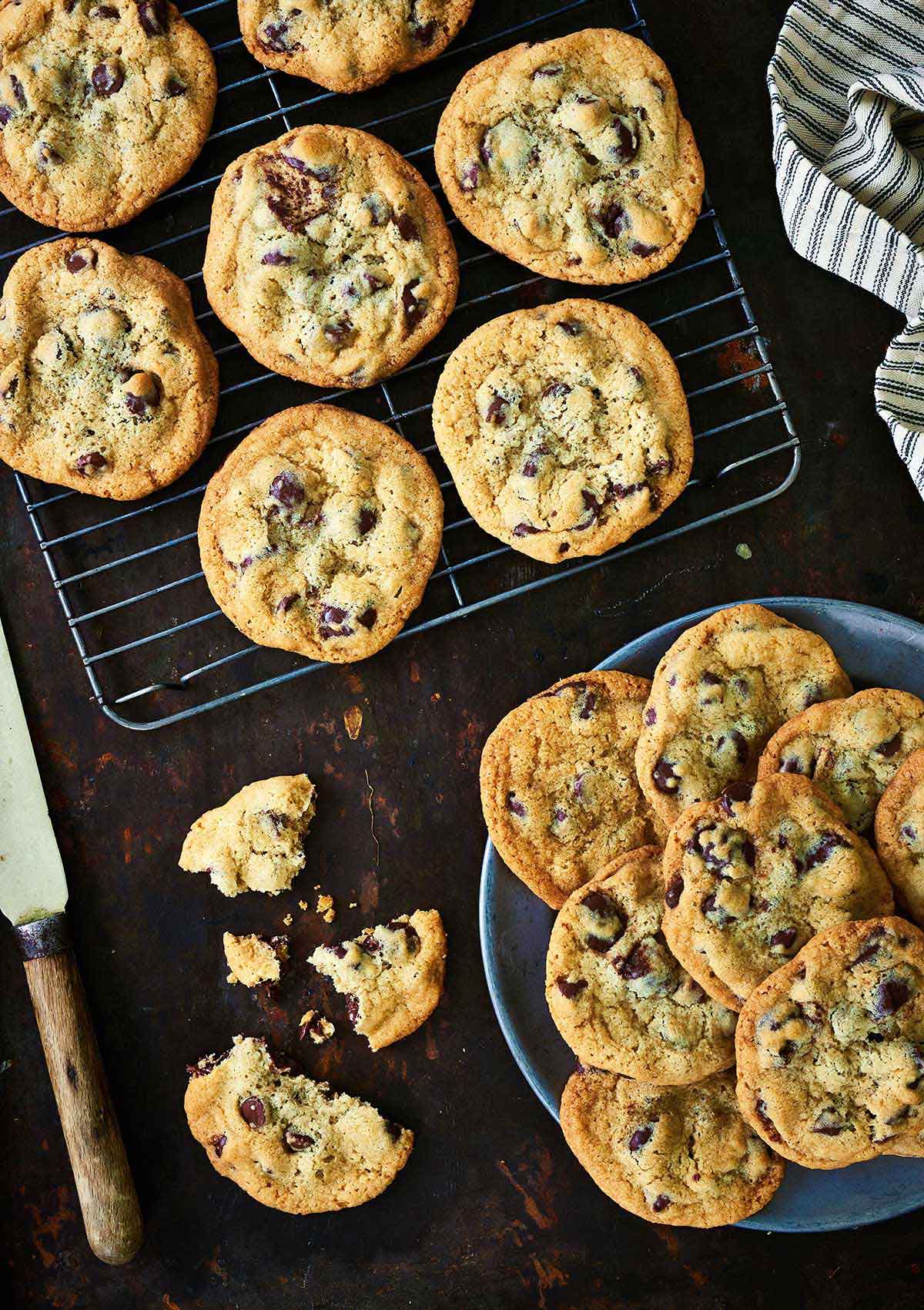 Freshly baked chocolate chip cookies on a cooling rack and on a plate
