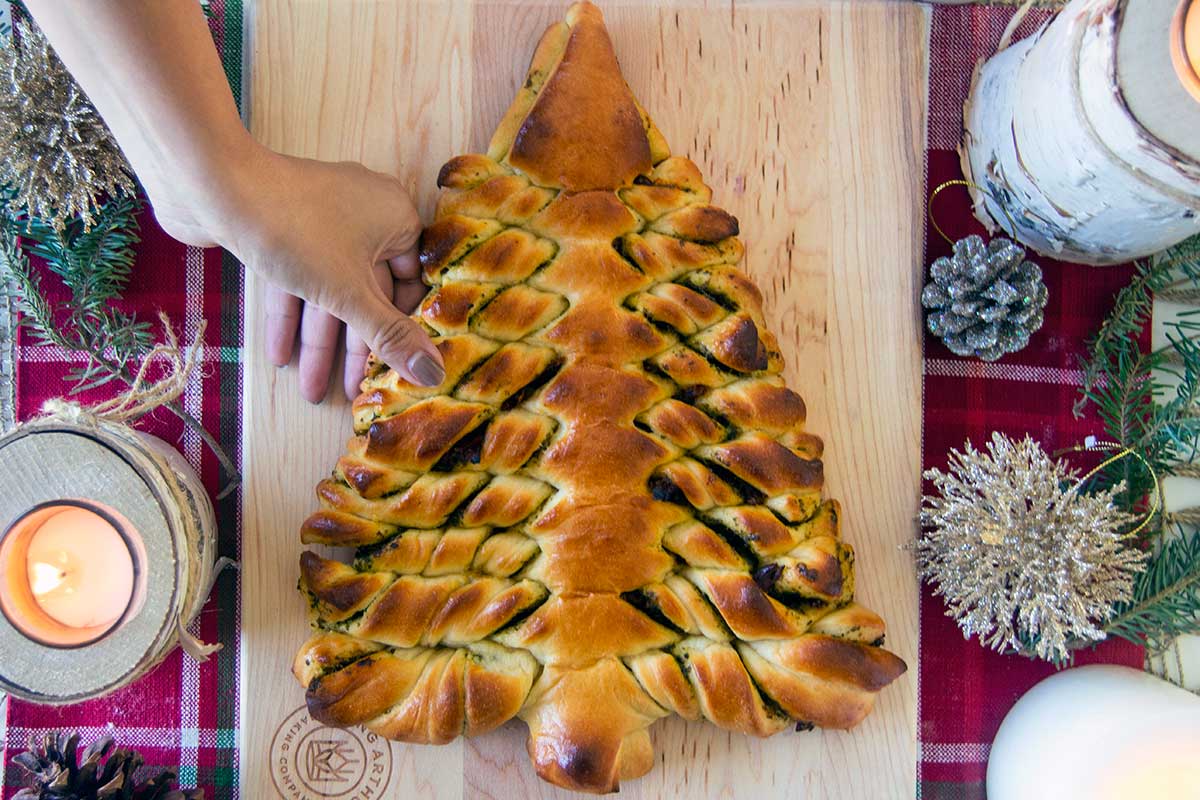 Baked Christmas tree bread with hand pulling off a piece