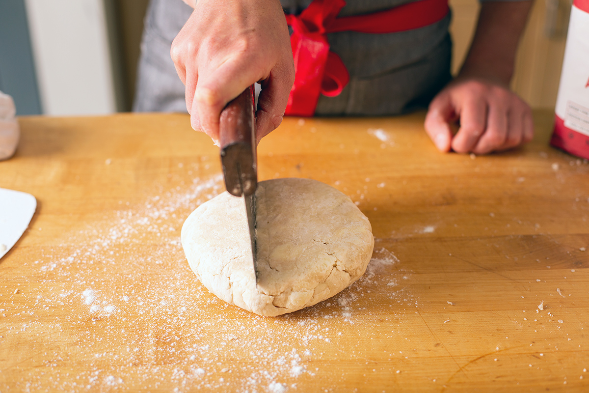 A baker dividing pie dough to make a top and bottom crust