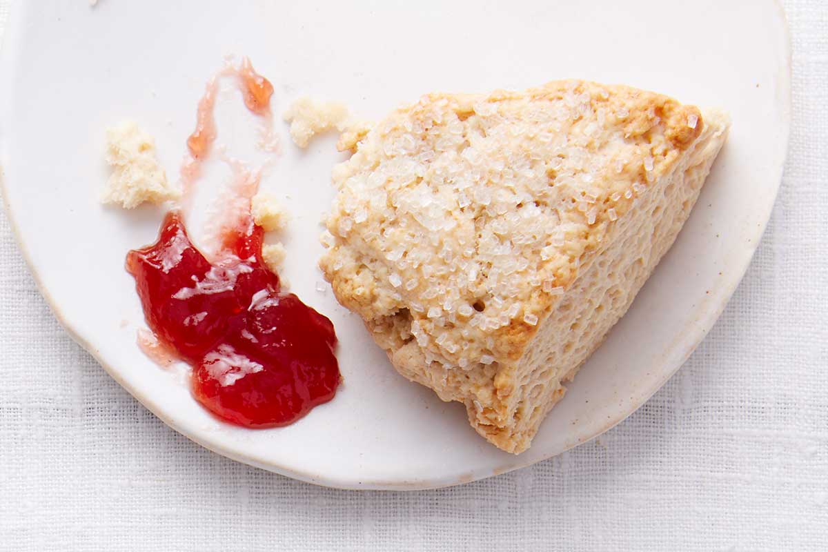A cream tea scone on a plate next to a schmear of jam