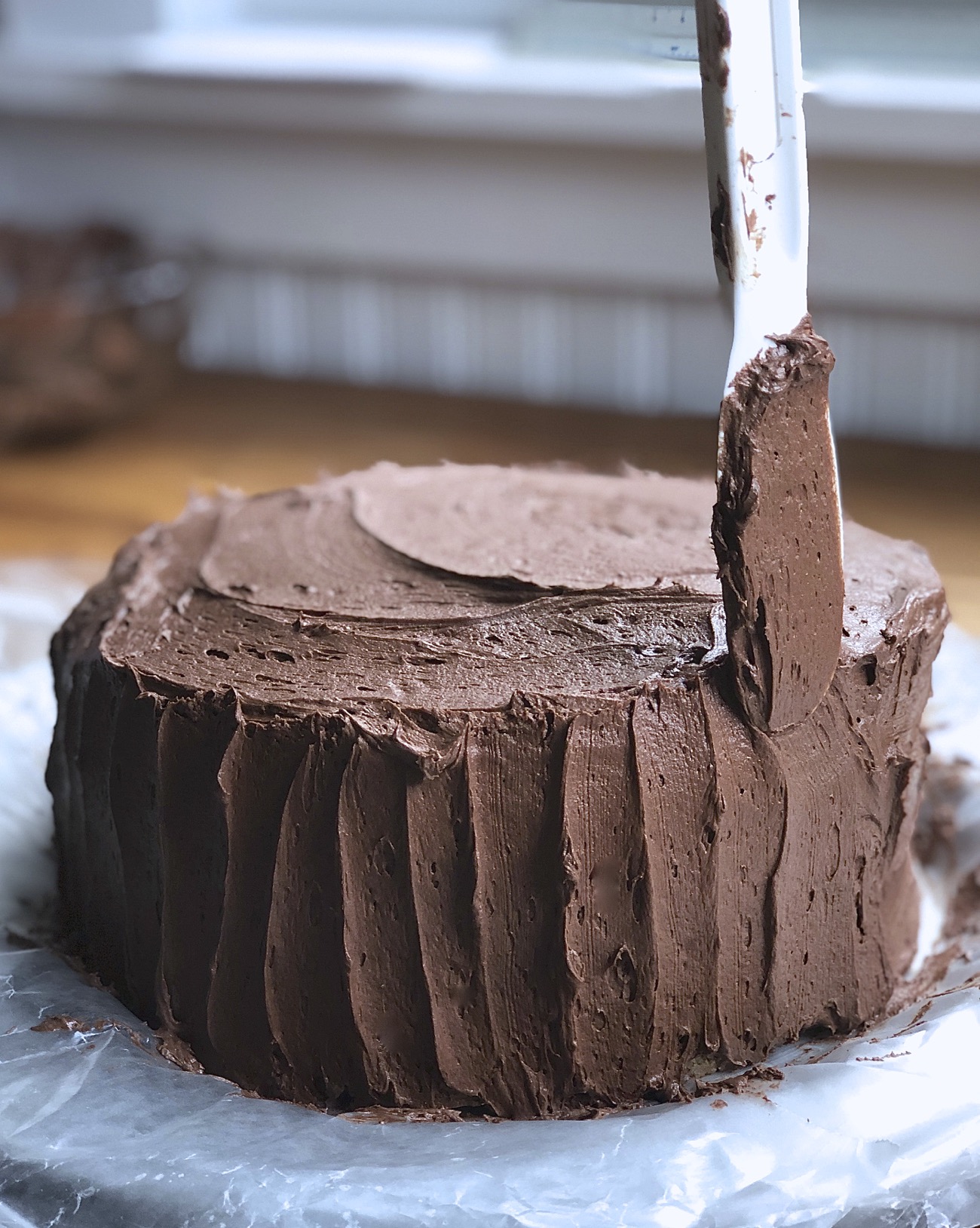 Using a nylon spatula to make vertical scallops in a chocolate-frosted double-layer yellow cake.