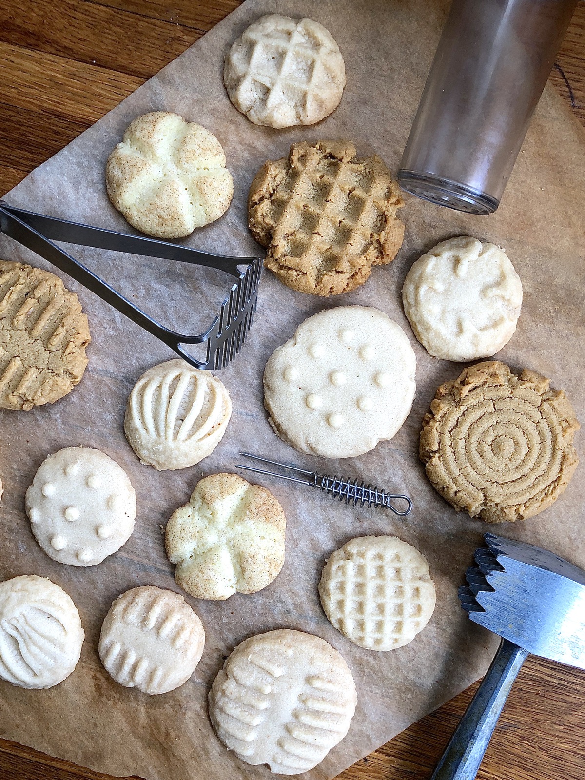 An assortment of cookies — peanut butter, shortbread, and Snickerdoodles — with imprinted tops, and the tools used to imprint.