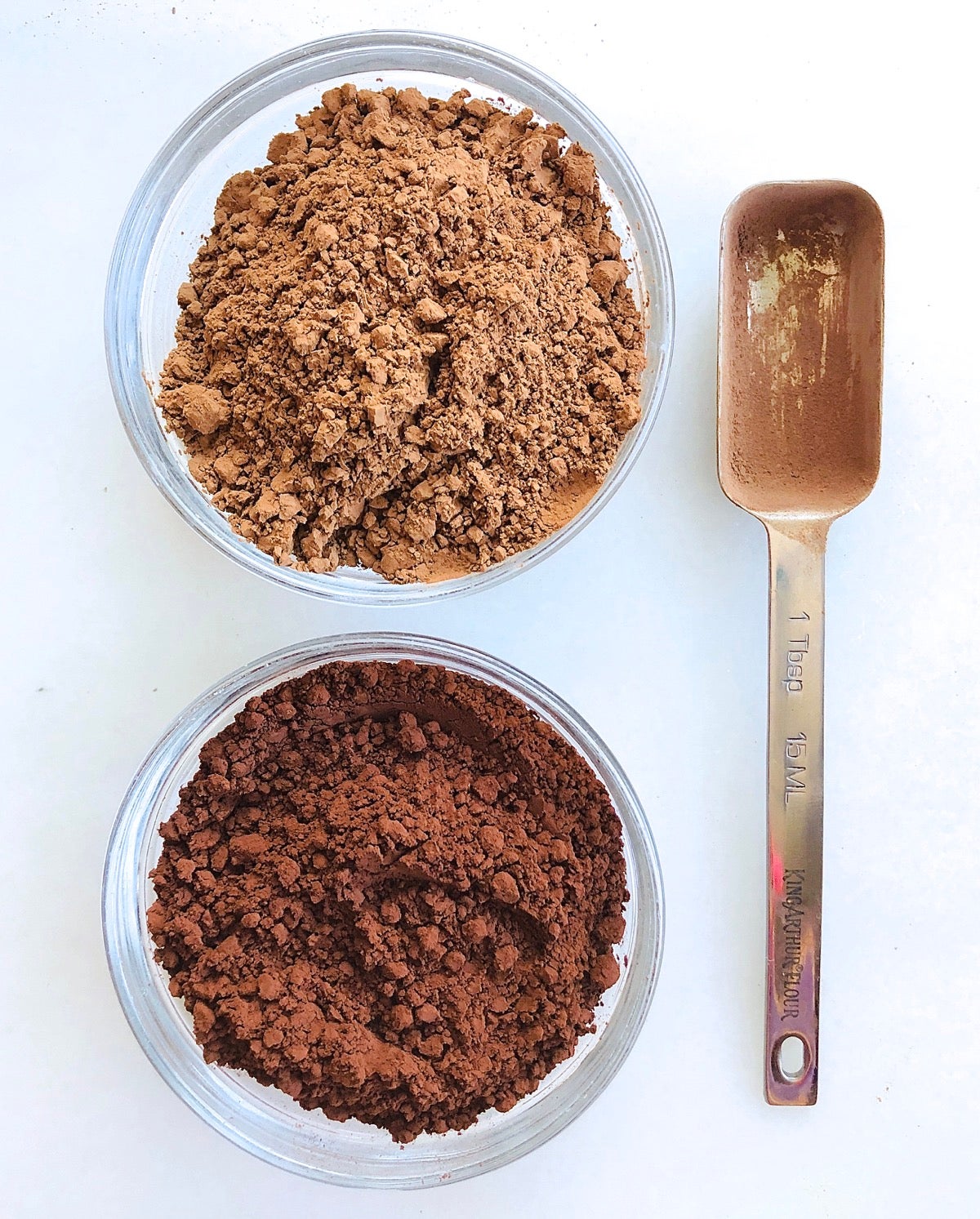 Natural cocoa and Dutch-process cocoa in small bowls showing color difference.