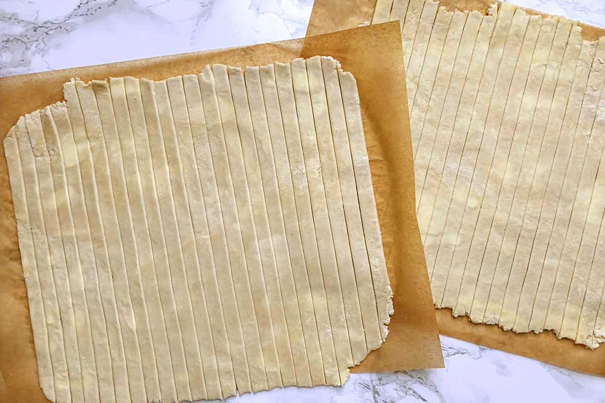 Two square sheets of rolled dough, cut into vertical strips