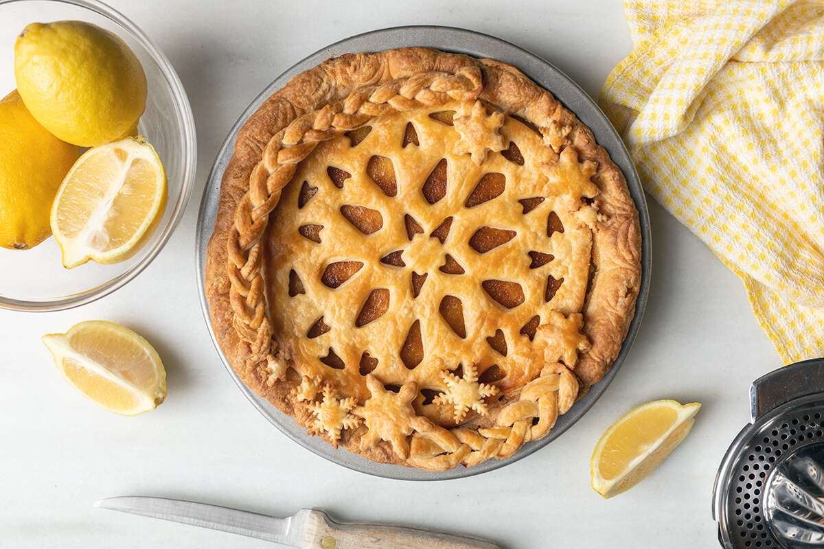 A lemon chess pie topped off with an intricate top crust on a kitchen table