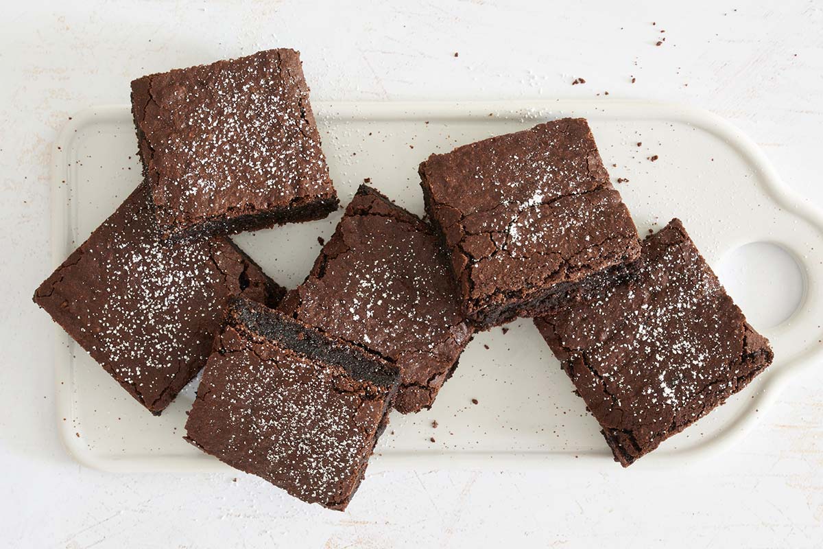 A platter of gluten-free brownies dusted with confectioners' sugar