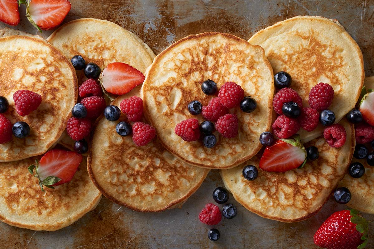 A tray of gluten-free pancakes topped with fresh berries