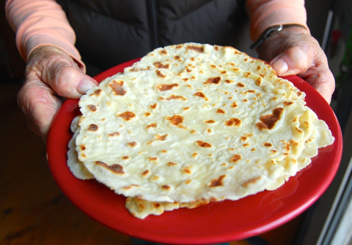 Hands holding a plate of lefse.