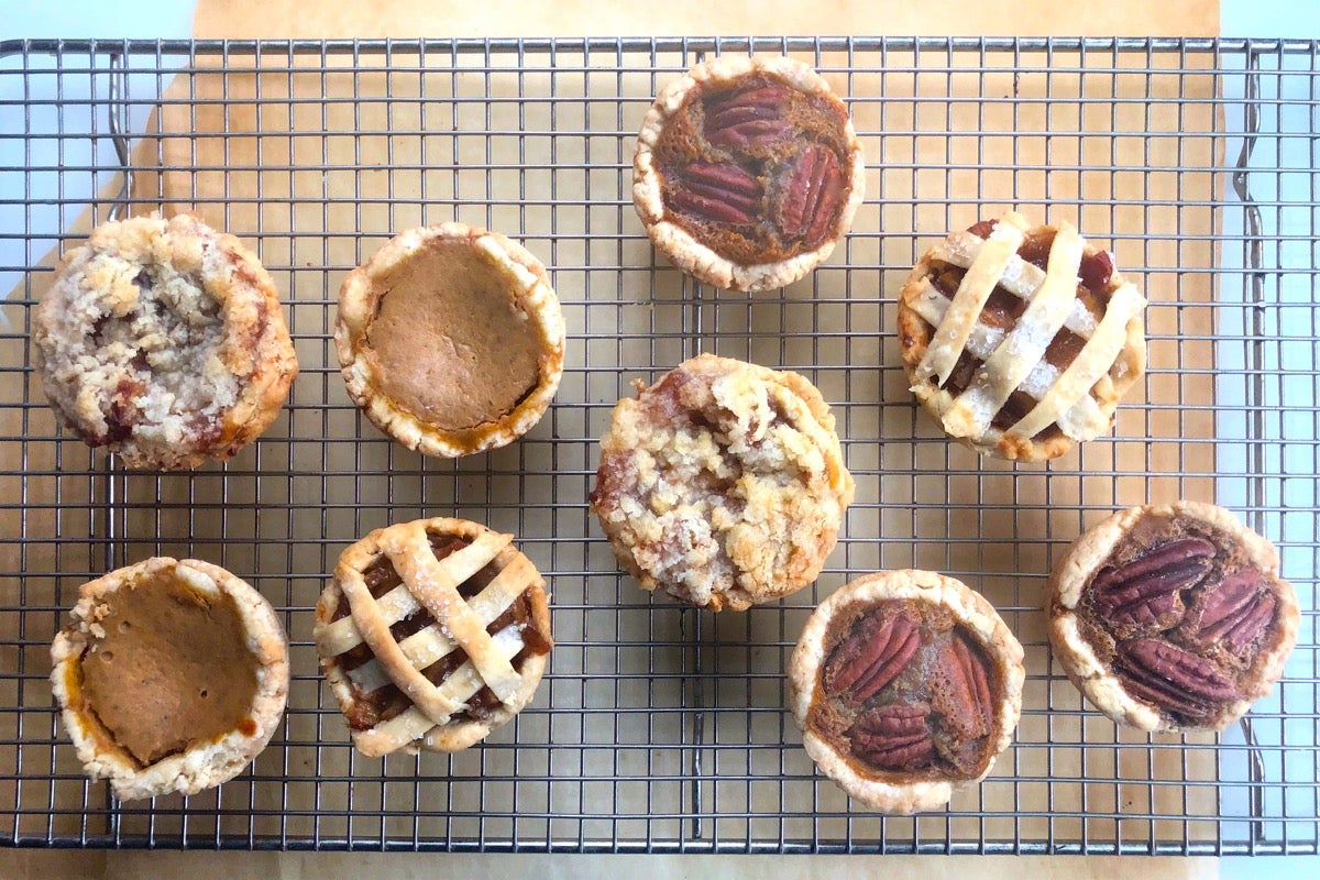 Mini pies — apple, pumpkin, and pecan — on a cooling rack.