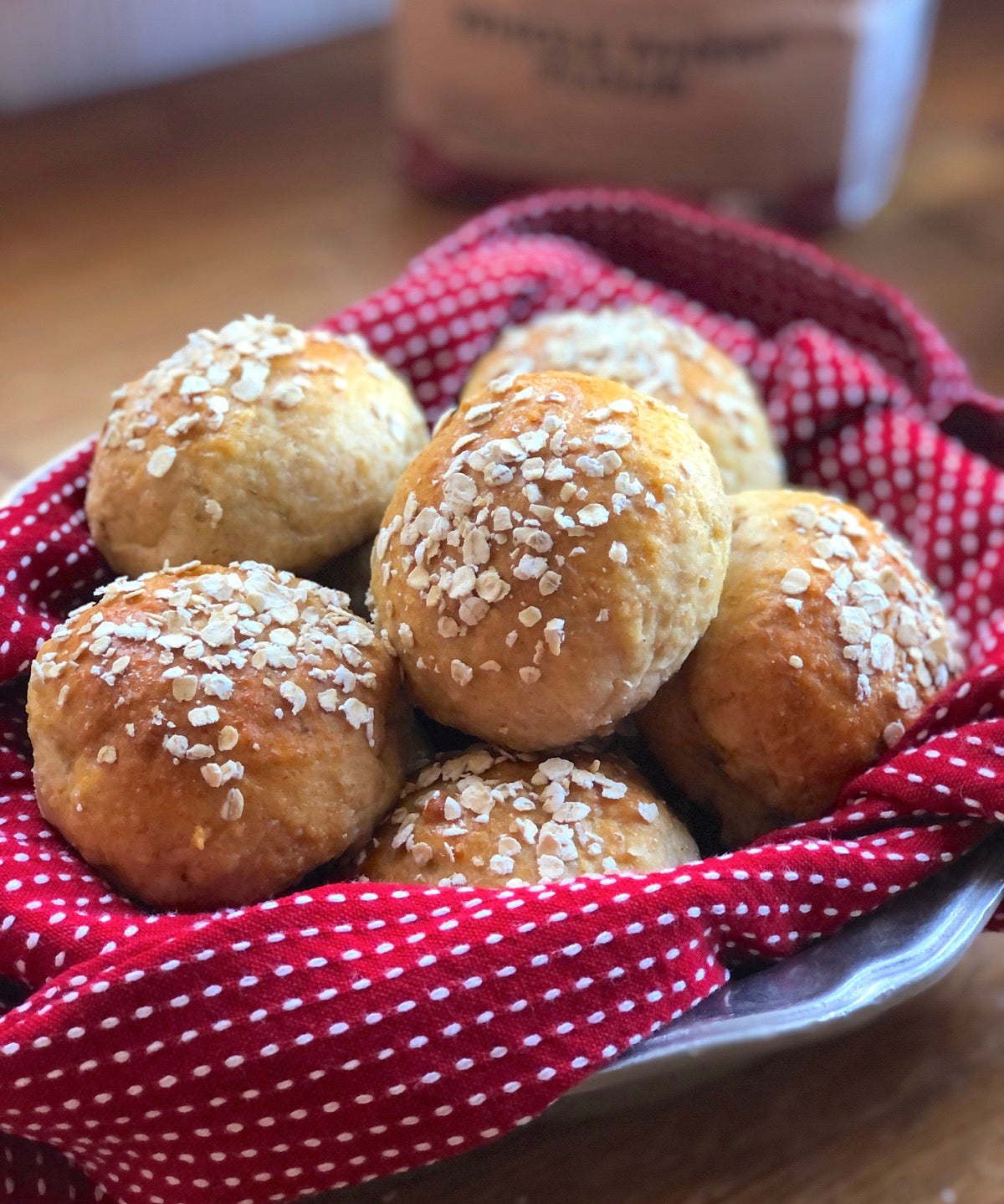 Whole grain dinner rolls in a bowl lined with a red towel
