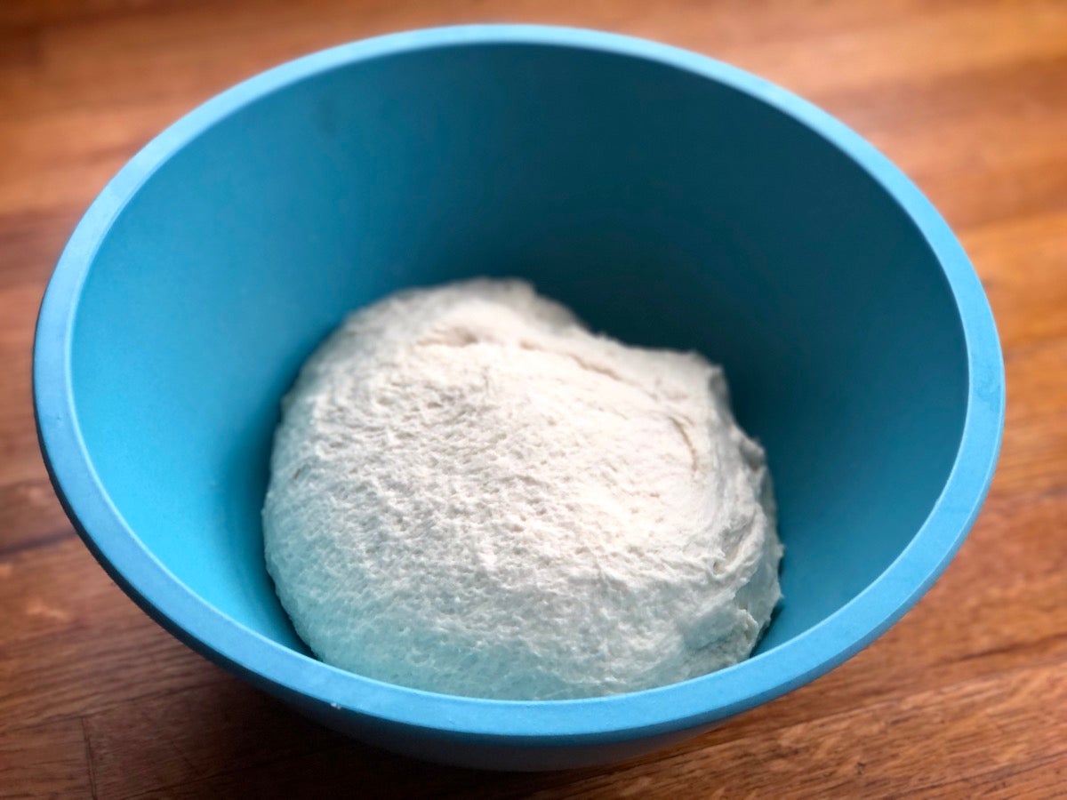 Soft dough in a blue bowl, ready to rise.