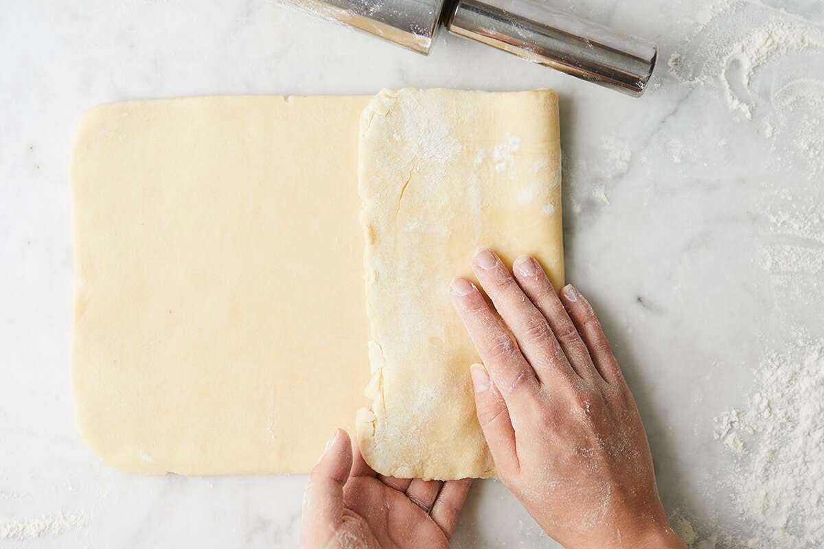 Hands folding laminated pastry dough into thirds