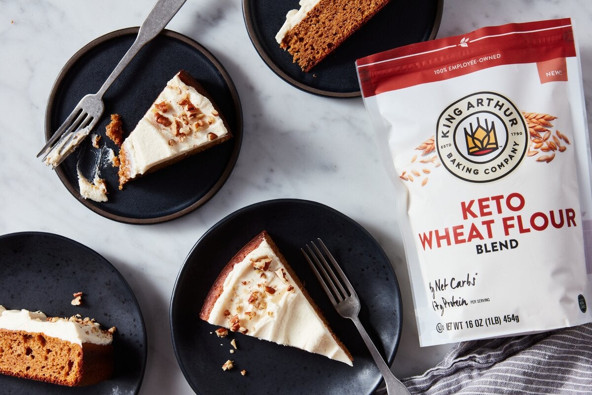 Slices of keto-friendly pumpkin cake topped off with cream cheese frosting next to a bag of King Arthur Keto Wheat Flour