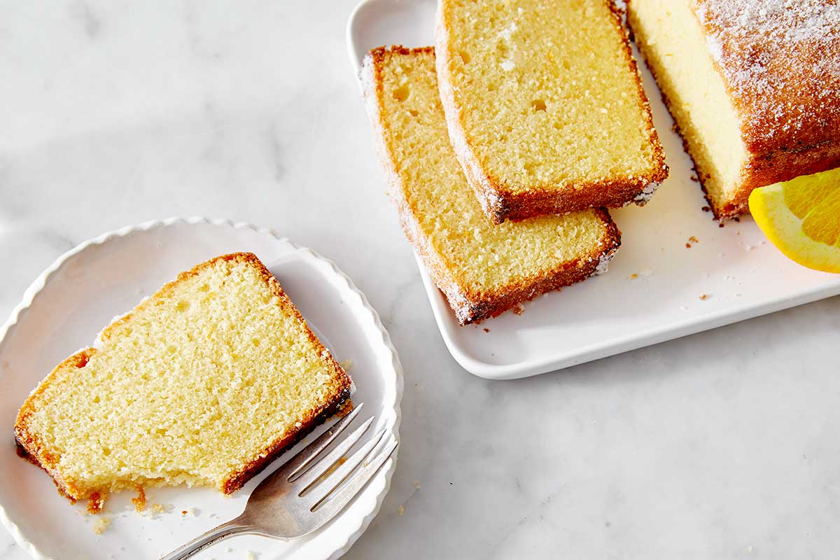 A loaf of lemon pound cake with a few slices on plates 